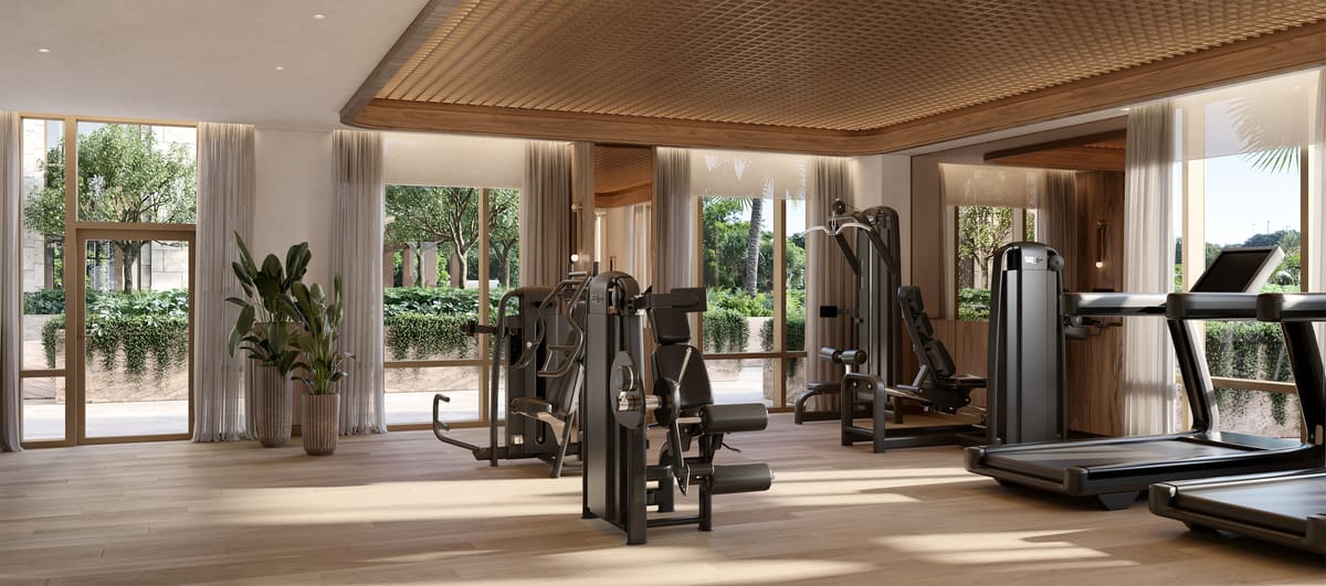 The fitness centre at Ponce Park Residences, opening through full-height glass onto the Zen Garden